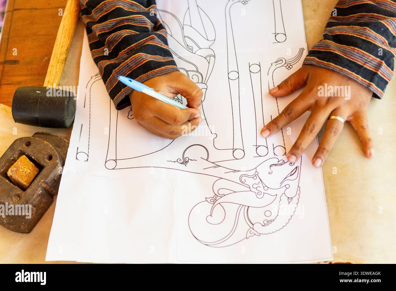 Un artisan dessine méticuleusement un design complexe pour une marionnette d'ombre traditionnelle wayang kulit. Ce processus artisanal met en valeur la culture javanaise Banque D'Images