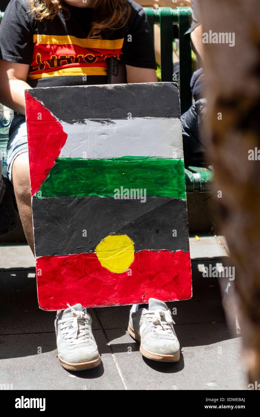 Panneau peint à la main combinant le drapeau aborigène et le drapeau palestinien tenu lors d'une manifestation pour les droits des indigènes en Australie, symbolisant la solidarité et Banque D'Images