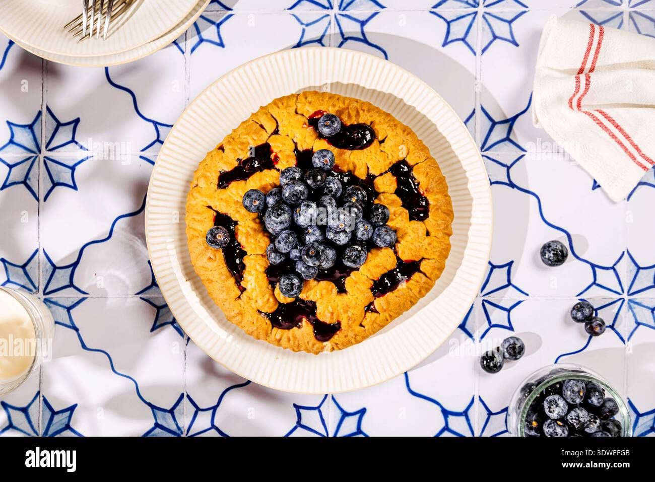 Un petit déjeuner appétissant composé d'une tarte dorée garnie de myrtilles fraîches et juteuses. Servi sur une table à motifs bleu et blanc, perfe Banque D'Images