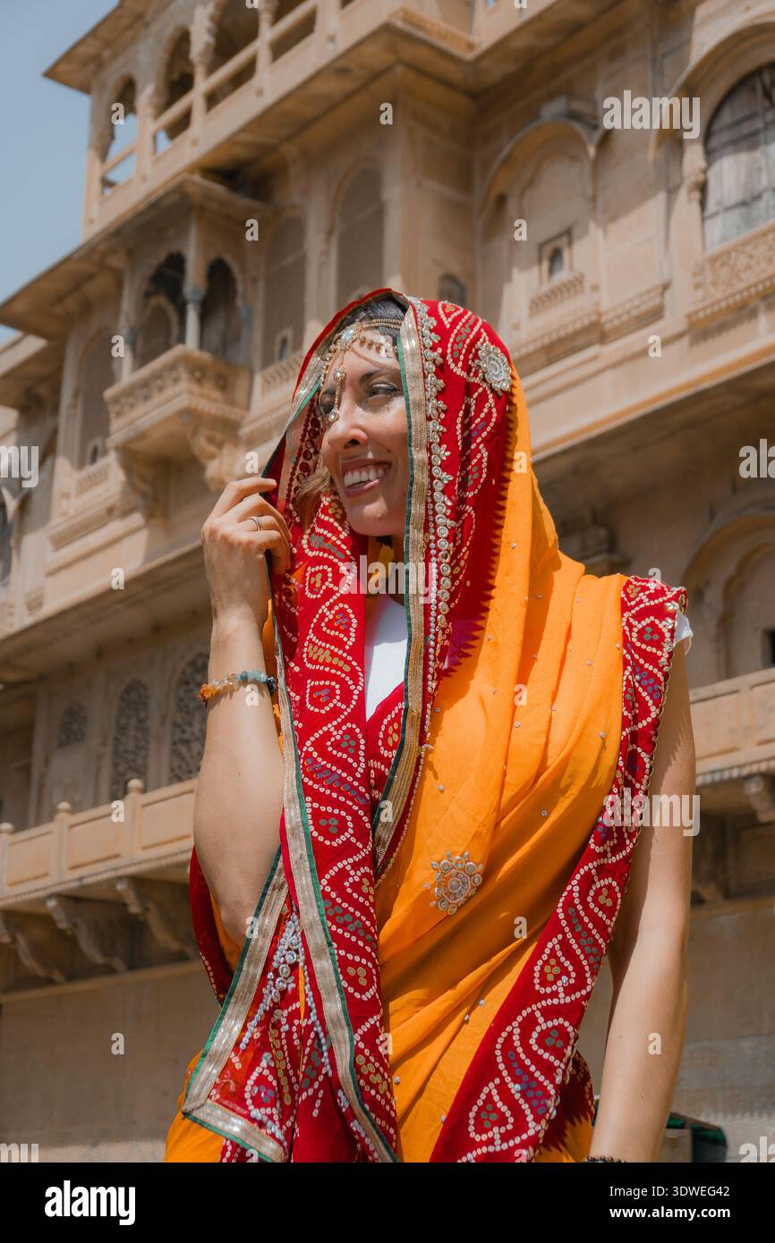 Femme en tenue traditionnelle vibrante se tient gracieusement devant un temple indien historique, mettant en valeur le riche patrimoine culturel et l'architecture de Banque D'Images