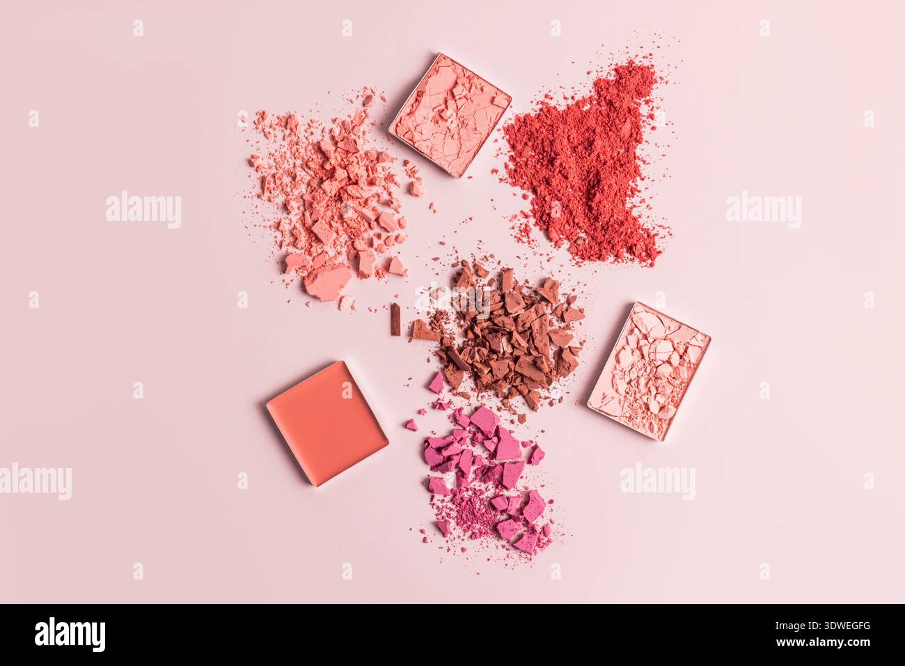 Un arrangement artistique de poudres de fard à joues assorties dans des tons de rose et de corail, mettant en valeur des textures et des compositions variées sur un dos doux et rose-fard Banque D'Images