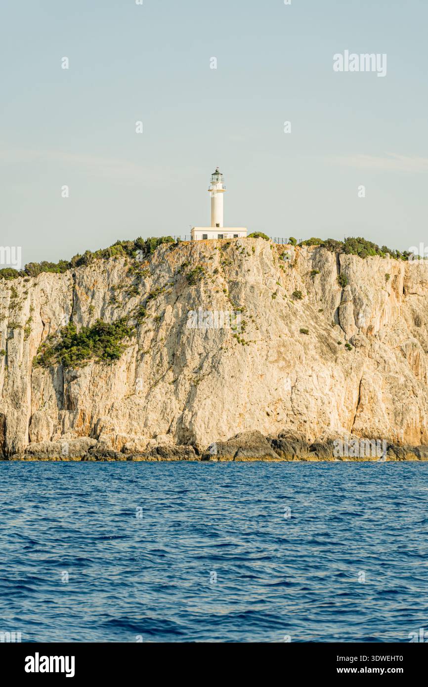 Un phare pittoresque perché sur une falaise accidentée en Grèce, surplombant la mer bleue profonde. La scène capture la sérénité et la beauté intemporelle de th Banque D'Images