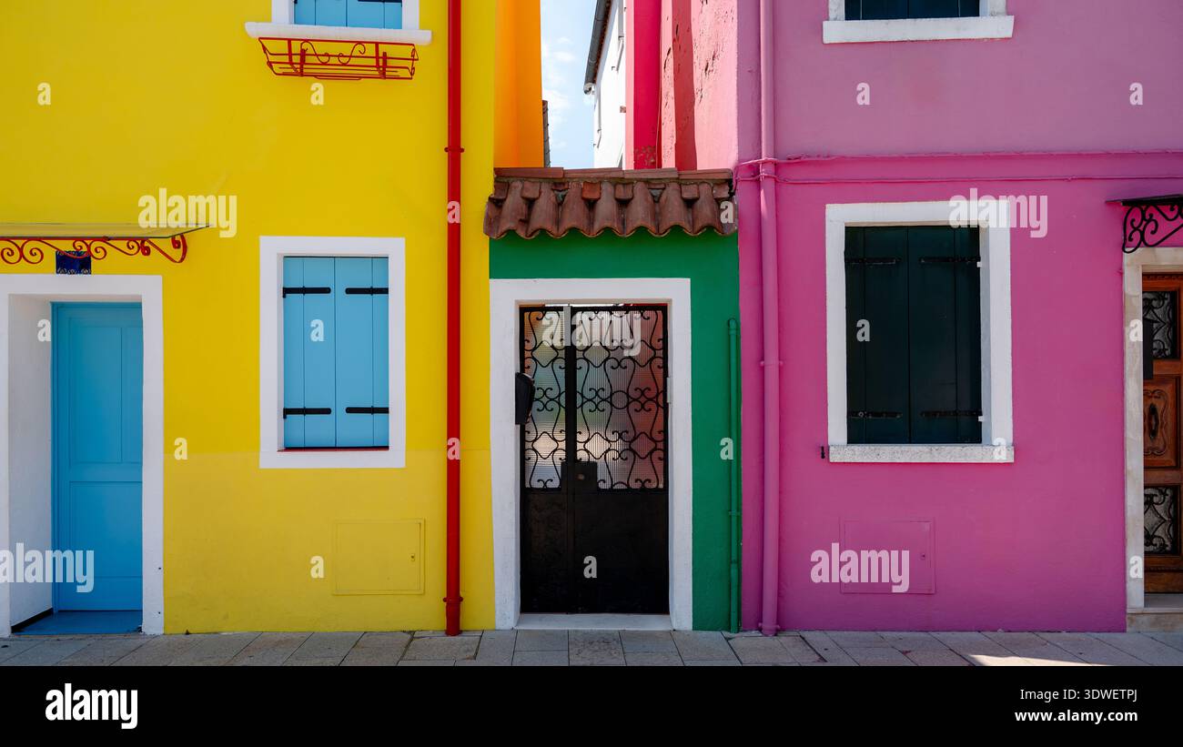 Les façades aux couleurs vives de l'île de Burano présentent les riches teintes de jaune, vert et rose, reflétant la culture vibrante et le charme de ces images Banque D'Images