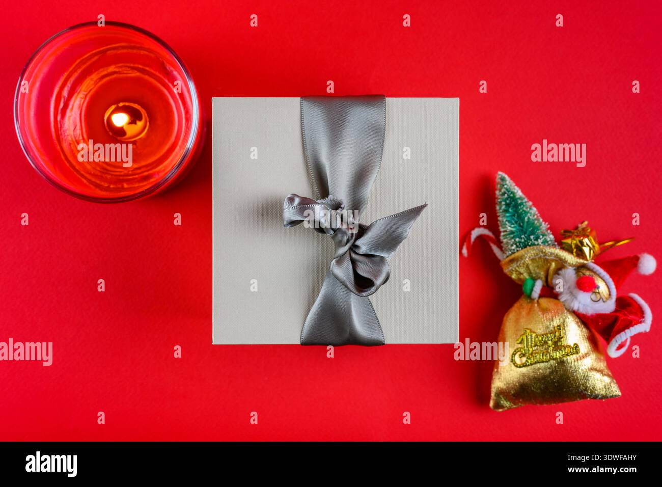 Un cadeau, une bougie du Père Noël sur fond rouge. Décoration de Noël. Banque D'Images