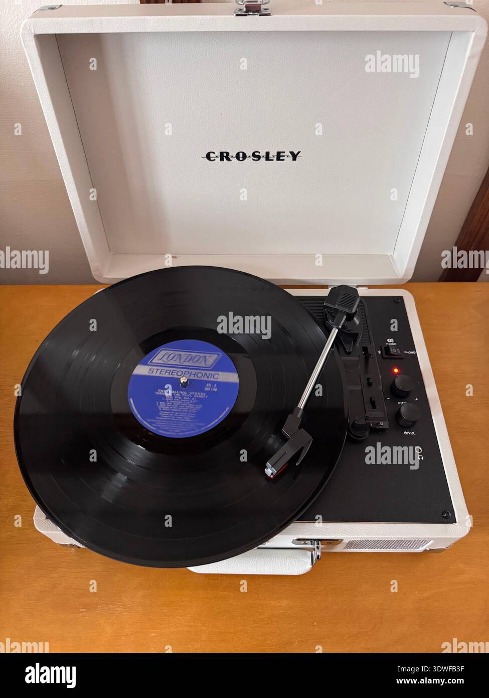 Lecteur de disques Crosley portable avec un LP vinyle tournant sur une table en bois, configuration rétro de la musique à la maison. Banque D'Images