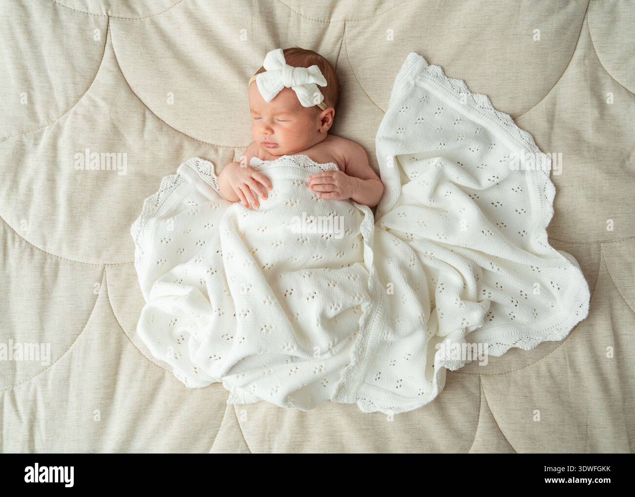 Bébé nouveau-né endormi centré sur un tissu neutre doux portant des vêtements blancs. Composition minimale symétrique idéale pour la mode bébé, parentale Banque D'Images