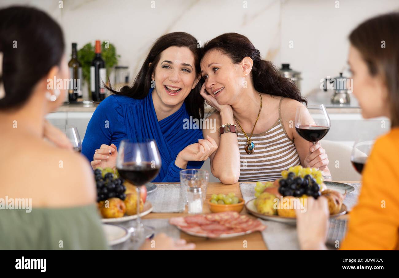 Des femmes heureuses se sont rassemblées autour d'une table festive ; participant à des discussions animées et appréciant les délices du vin Banque D'Images
