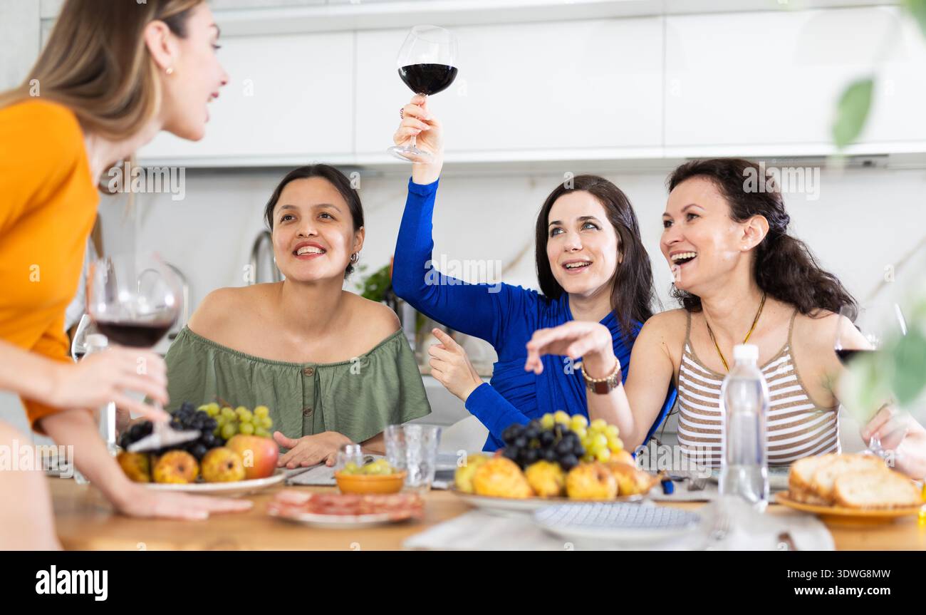 Des femmes heureuses se sont rassemblées autour d'une table festive ; participant à des discussions animées et appréciant les délices du vin Banque D'Images
