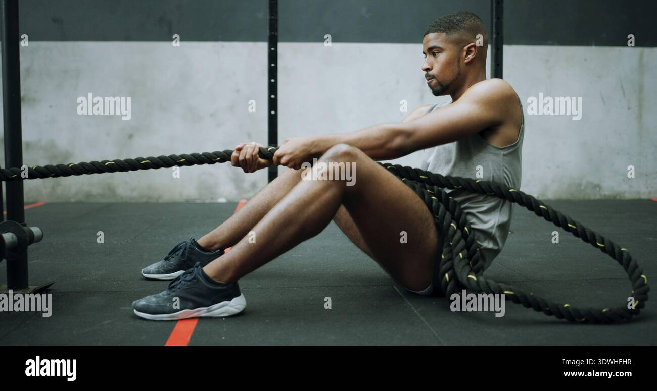 Homme, cordes de combat et entraînement sur le sol de gymnastique avec traction, exercice intense et résilience avec défi. Personne, forme physique et puissance avec la respiration Banque D'Images