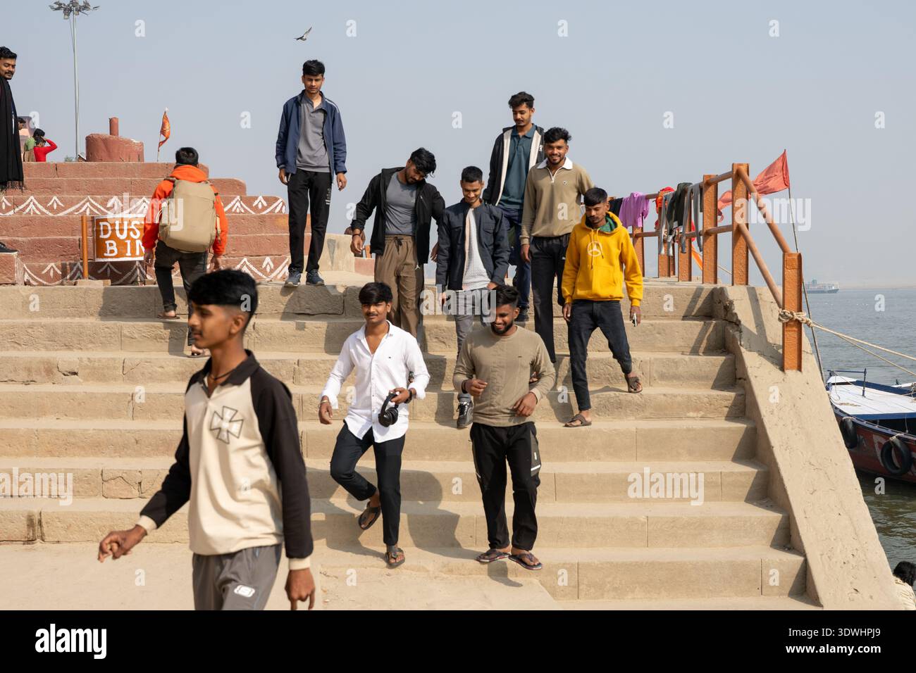 De jeunes hommes descendent accidentellement des marches de pierre près de la rive de la rivière à Varanasi, en Inde, par temps clair. Banque D'Images