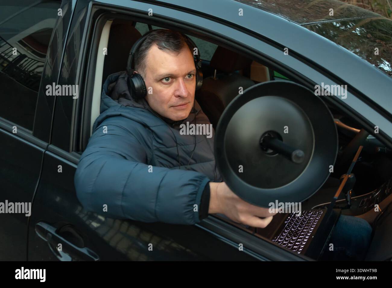 Un opérateur équipé d'écouteurs effectue une surveillance audio à l'aide d'un microphone directionnel et d'un ordinateur portable Banque D'Images