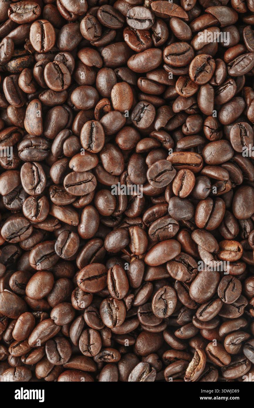 Grains de café noirs en studio. Grains de café fraîchement torréfiés comme fond de texture Banque D'Images