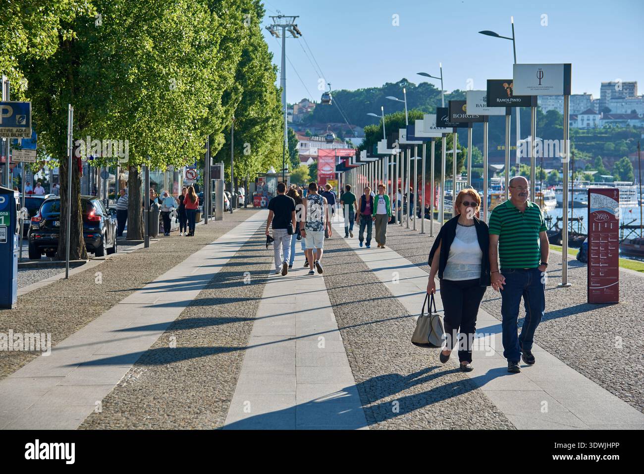 Les gens marchant le long de la promenade de Cais de Gaia bordée de panneaux de cave à vin de Porto et d'arbres, Vila Nova de Gaia, Porto, Portugal, Europe Banque D'Images