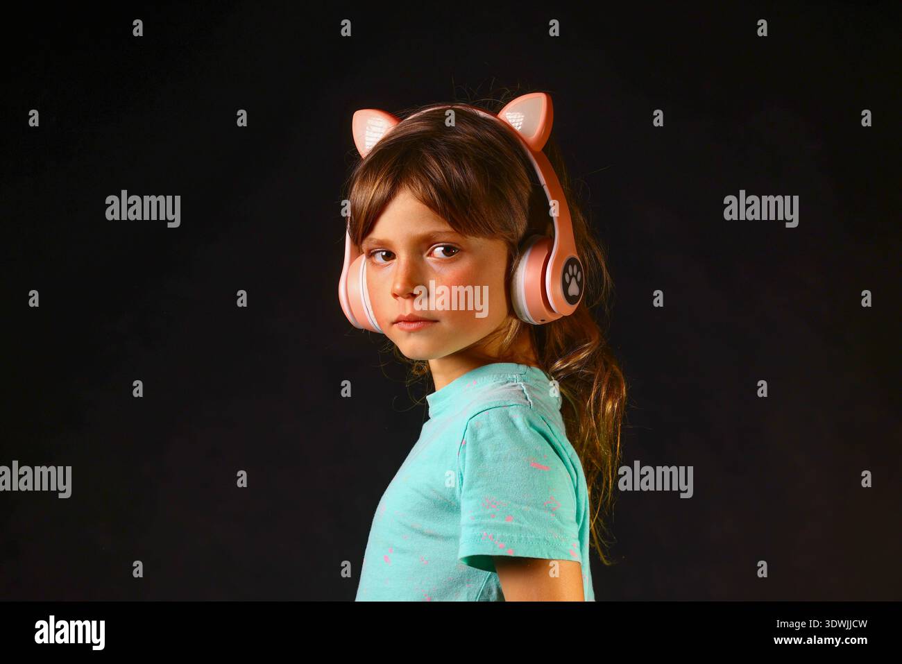 Fille écoutant de la musique tout en se concentrant dans un cadre moderne sombre, exprimant la concentration de l'enfance, l'apprentissage calme et une passion naturelle pour le son Banque D'Images
