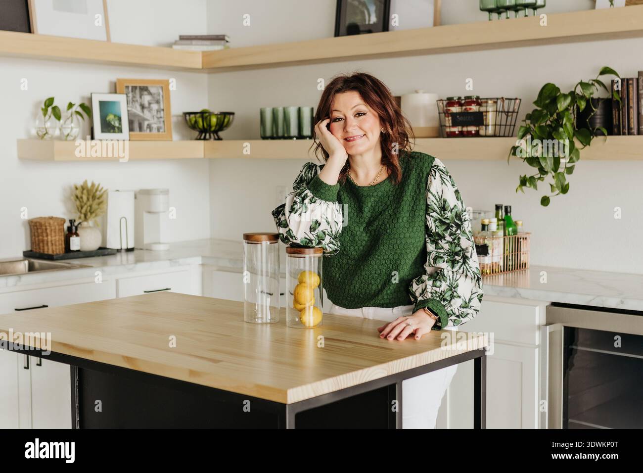 Femme se penche coude sur le pot en verre plein de citrons alors qu'elle est dans la cuisine Banque D'Images
