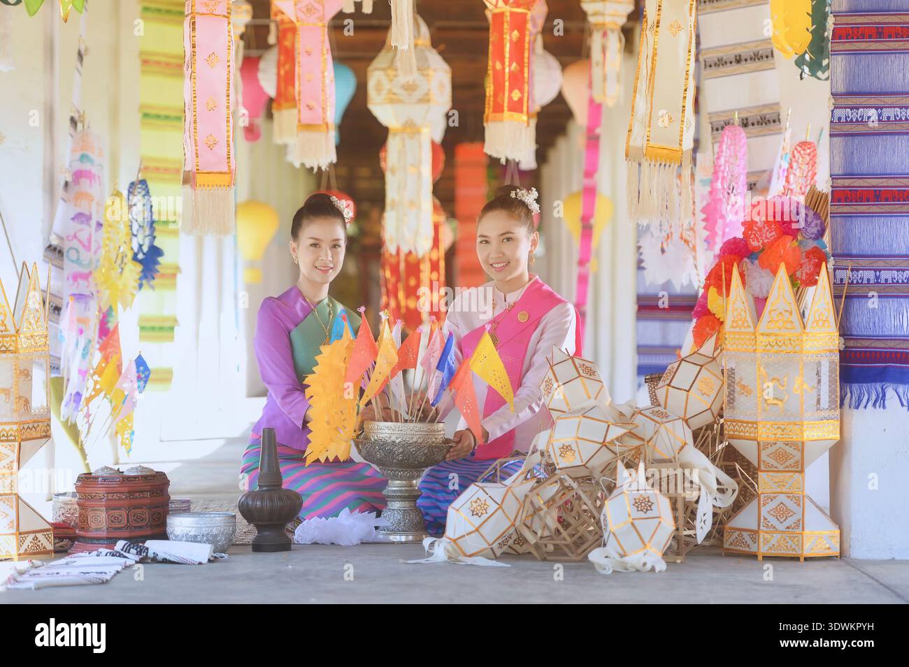 Deux jeunes femmes en vêtements traditionnels Lanna Thai assis devant un temple, Wat Intharawat, Chiang mai, Thaïlande Banque D'Images