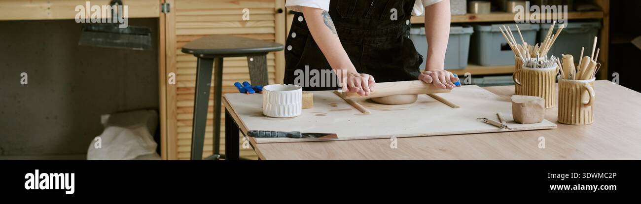 En-tête de femme façonnant l'argile avec Rolling PIN dans Pottery Studio Banque D'Images