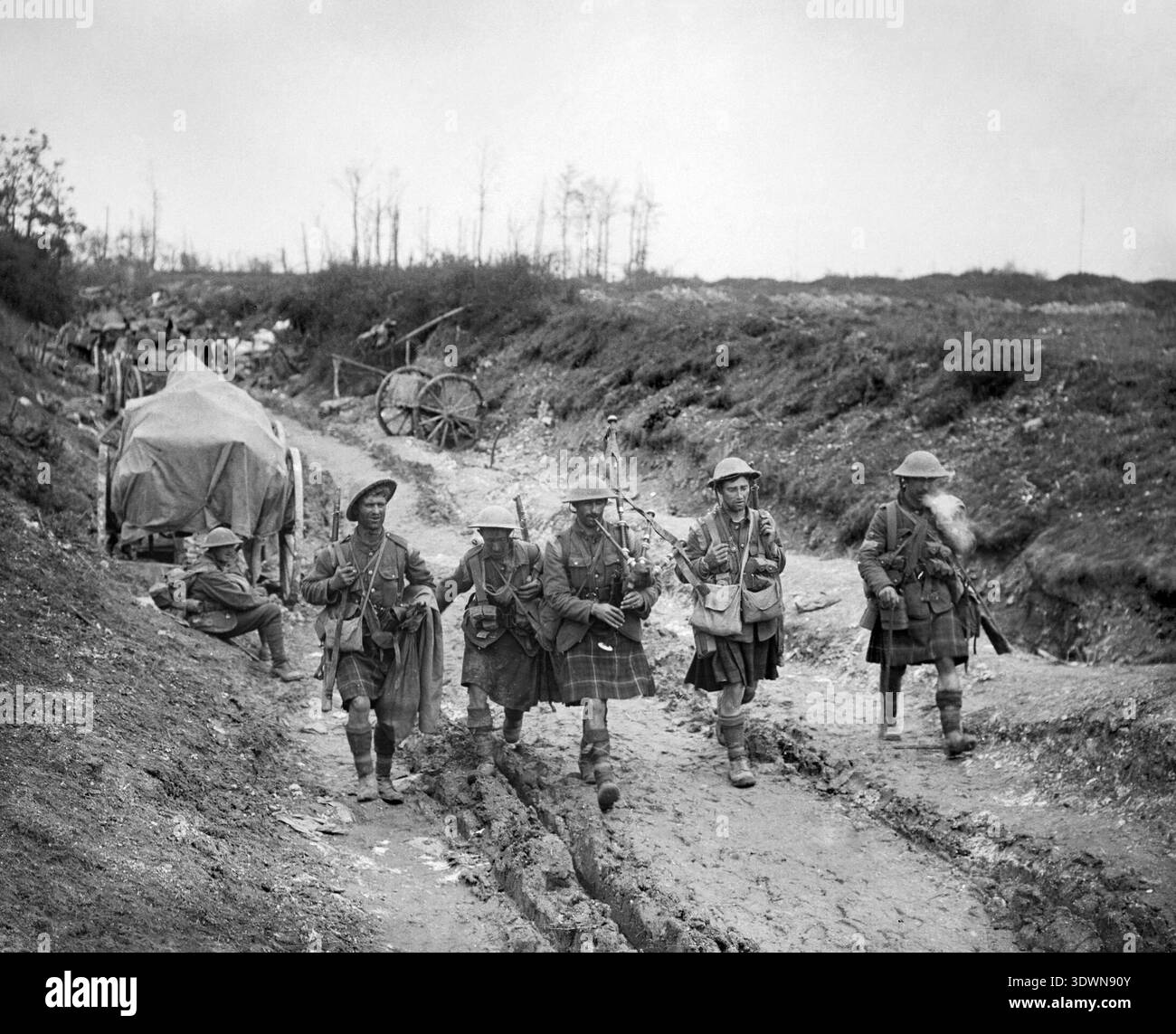 Cette photographie poignante de John Warwick Brooke capture un cornemuse du 7th Seaforth Highlanders conduisant quatre hommes de la 26th Brigade de retour des tranchées après l'attaque de Longueval le 14 juillet 1916. L'image, datant de la première Guerre mondiale, représente les soldats en kilts naviguant sur une piste boueuse, reflétant les dures réalités des conditions de guerre. Banque D'Images