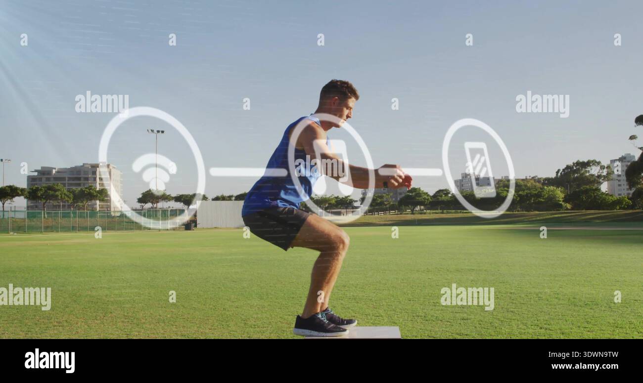 Squatting homme tenant la balle brune sur la boîte plyo au terrain de sport, portant le réservoir bleu, des icônes de superposition Banque D'Images