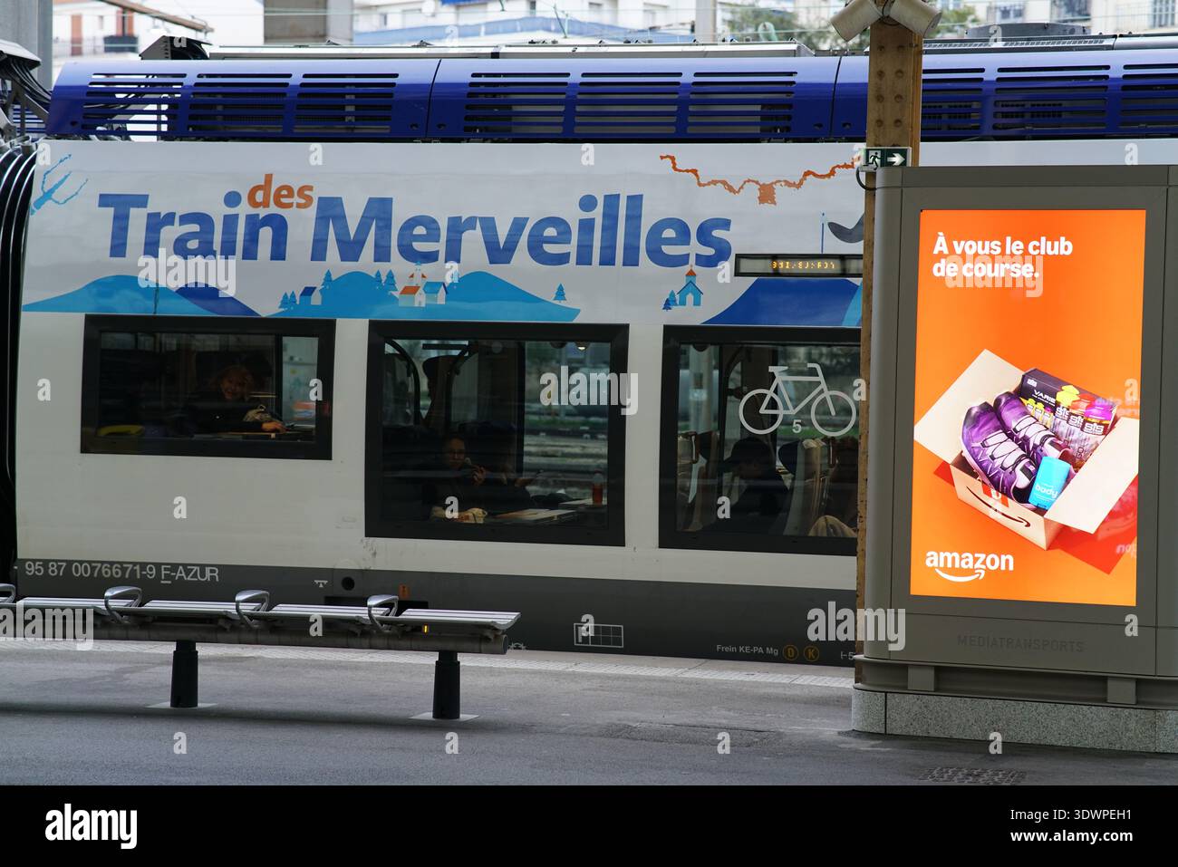 Gros plan de la calèche bleue du train des merveilles avec des graphismes montagneux et une publicité shopping Amazon avec vélo et boîte sur le quai de la gare de Nice. Banque D'Images