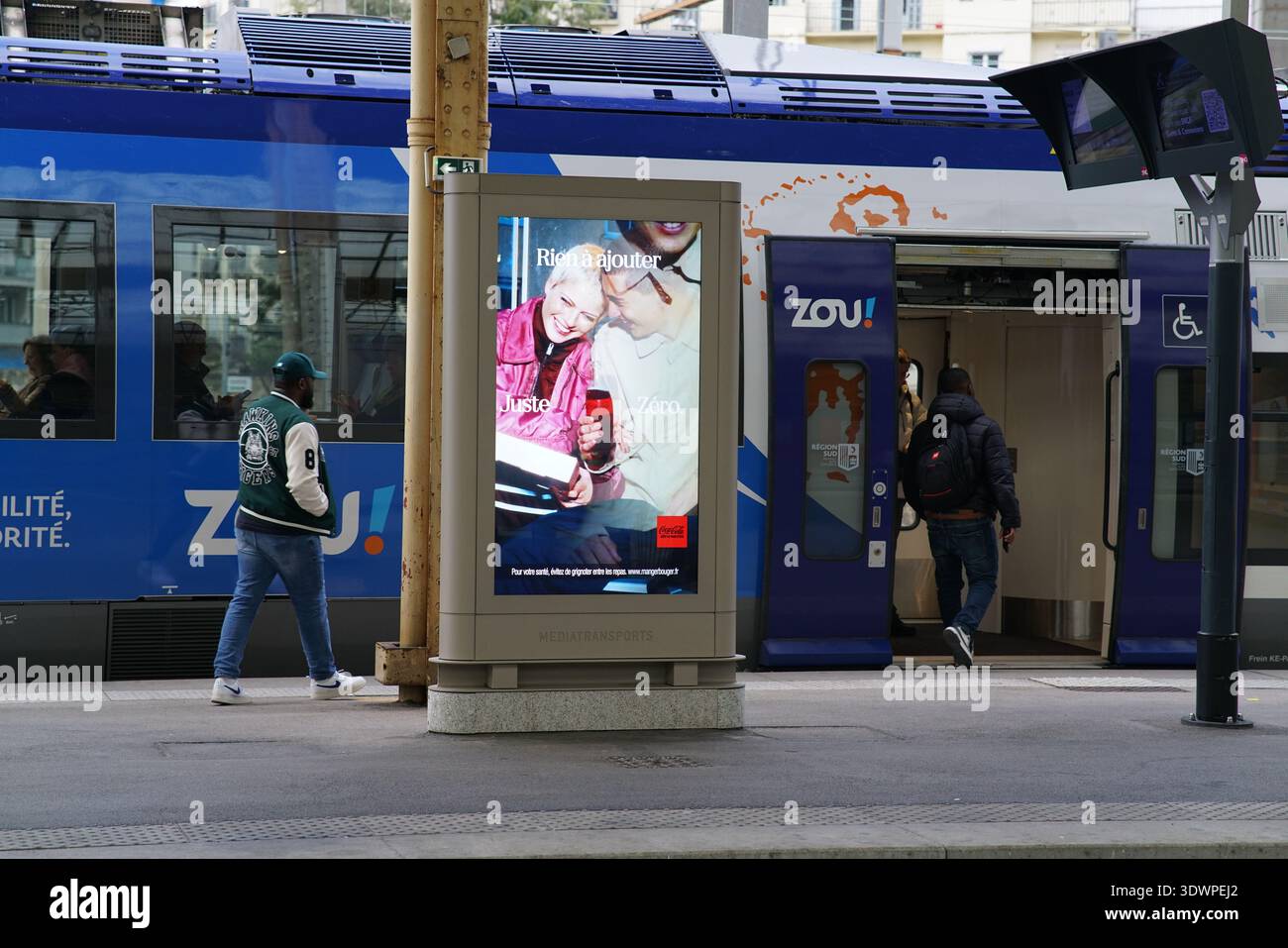Un grand panneau publicitaire à la gare de Nice annonce la campagne « plaisir d'hiver » de Zou avec un joyeux couple de personnes âgées dégustant des boissons chaudes Banque D'Images