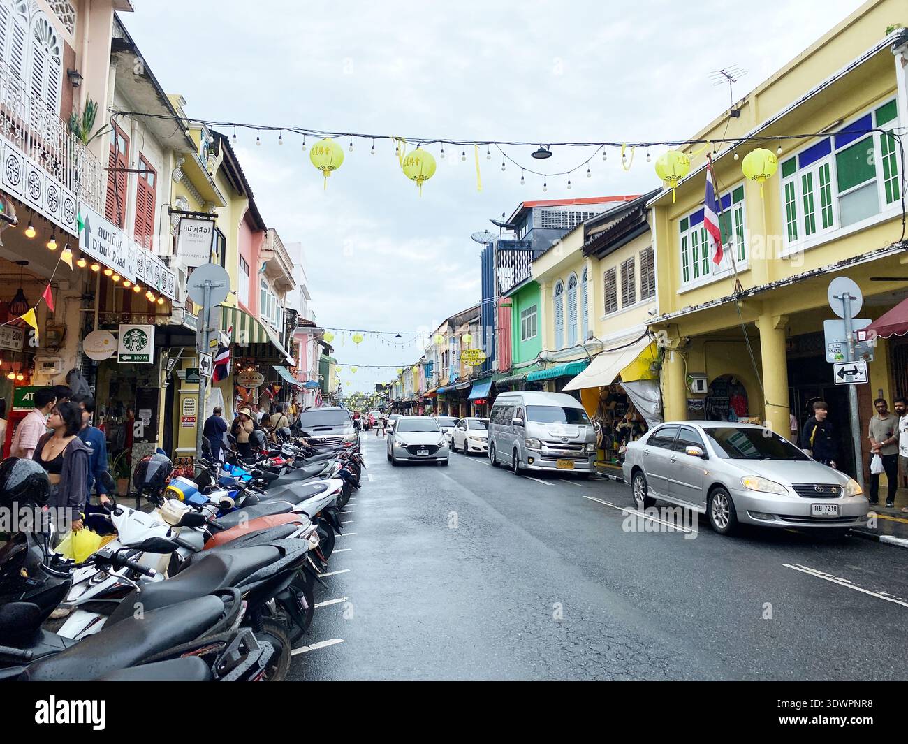 Phuket, Thaïlande - 28 octobre 2025 : L'architecture coloniale de la vieille ville de Phuket présente des couleurs vives, avec des motos garées et des voitures qui passent sous les yeux Banque D'Images