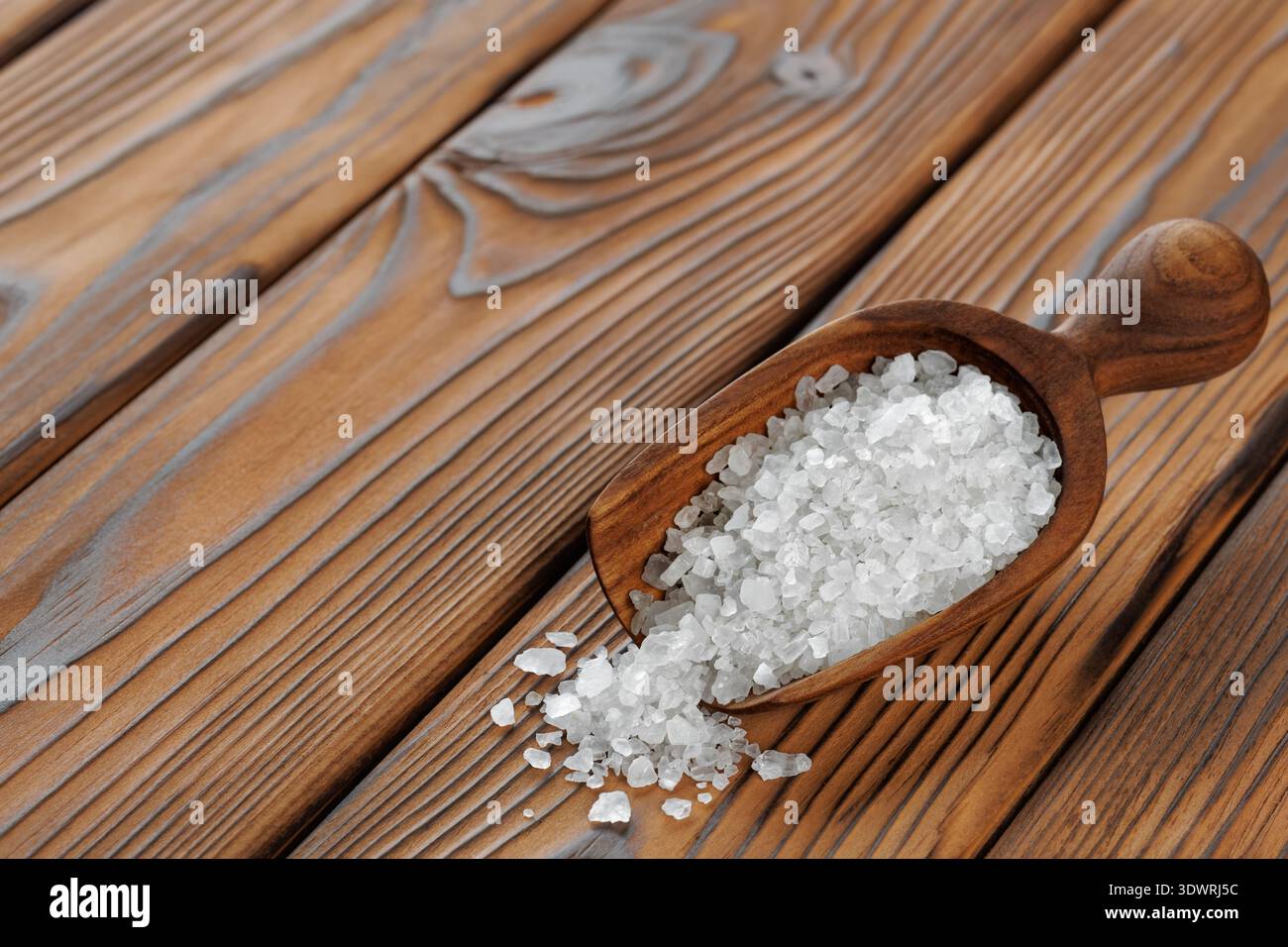 Sel de mer dans la cuillère sur la table en bois brun Banque D'Images