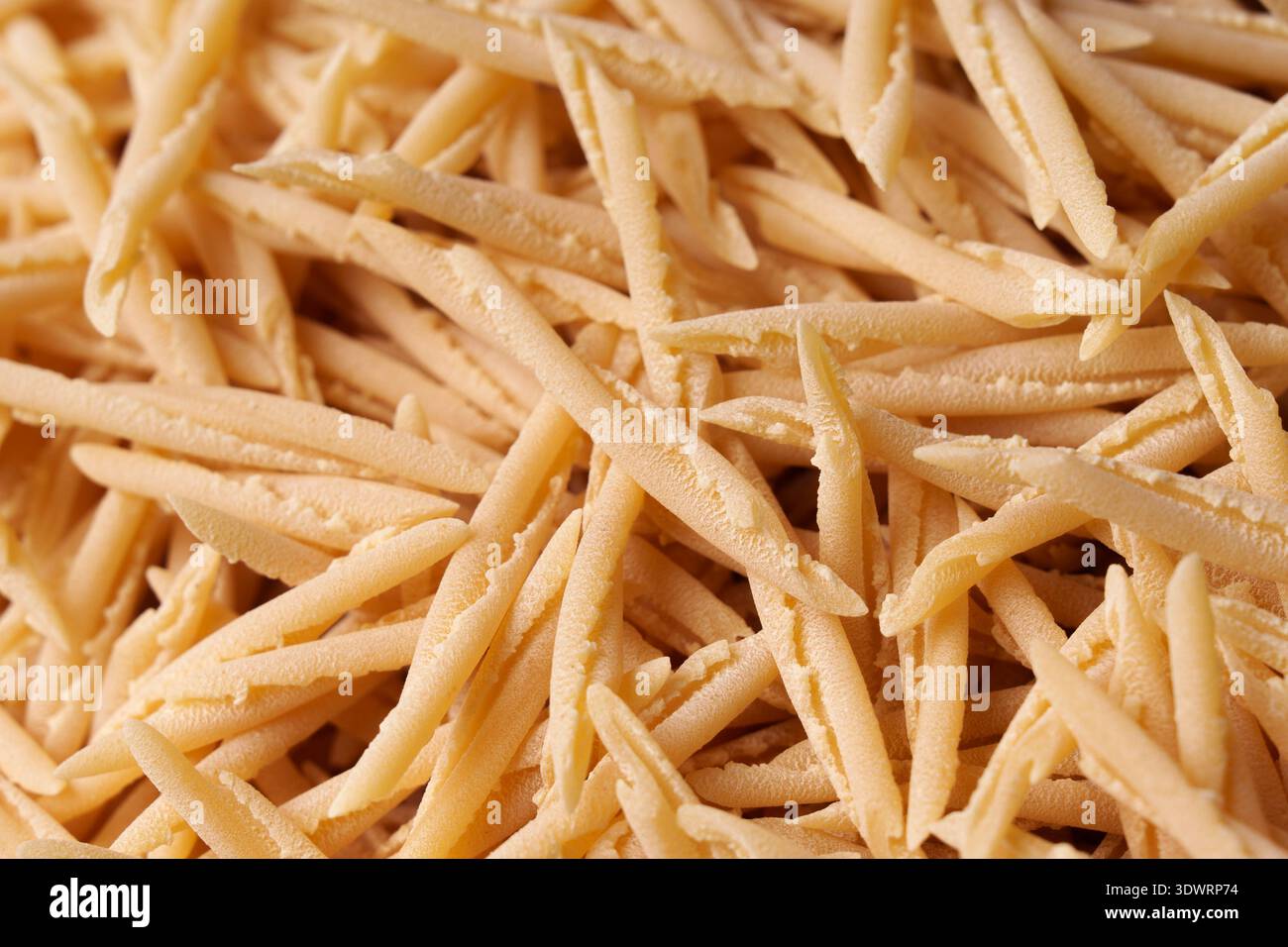 Trofie de pâtes italiennes sèches – texture et fond pour le design culinaire. Banque D'Images