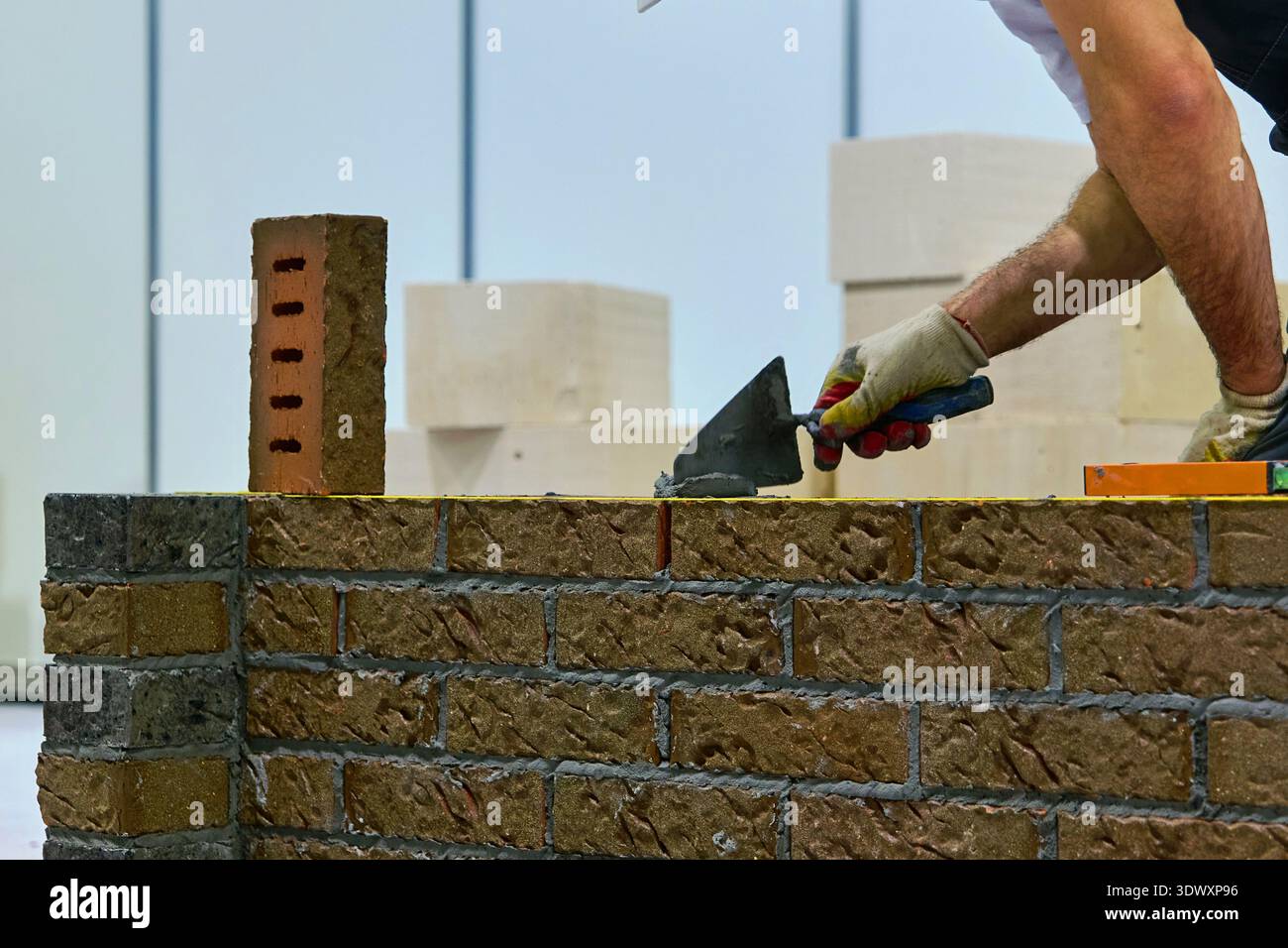 constructeur le maçon pose un mur de briques Banque D'Images