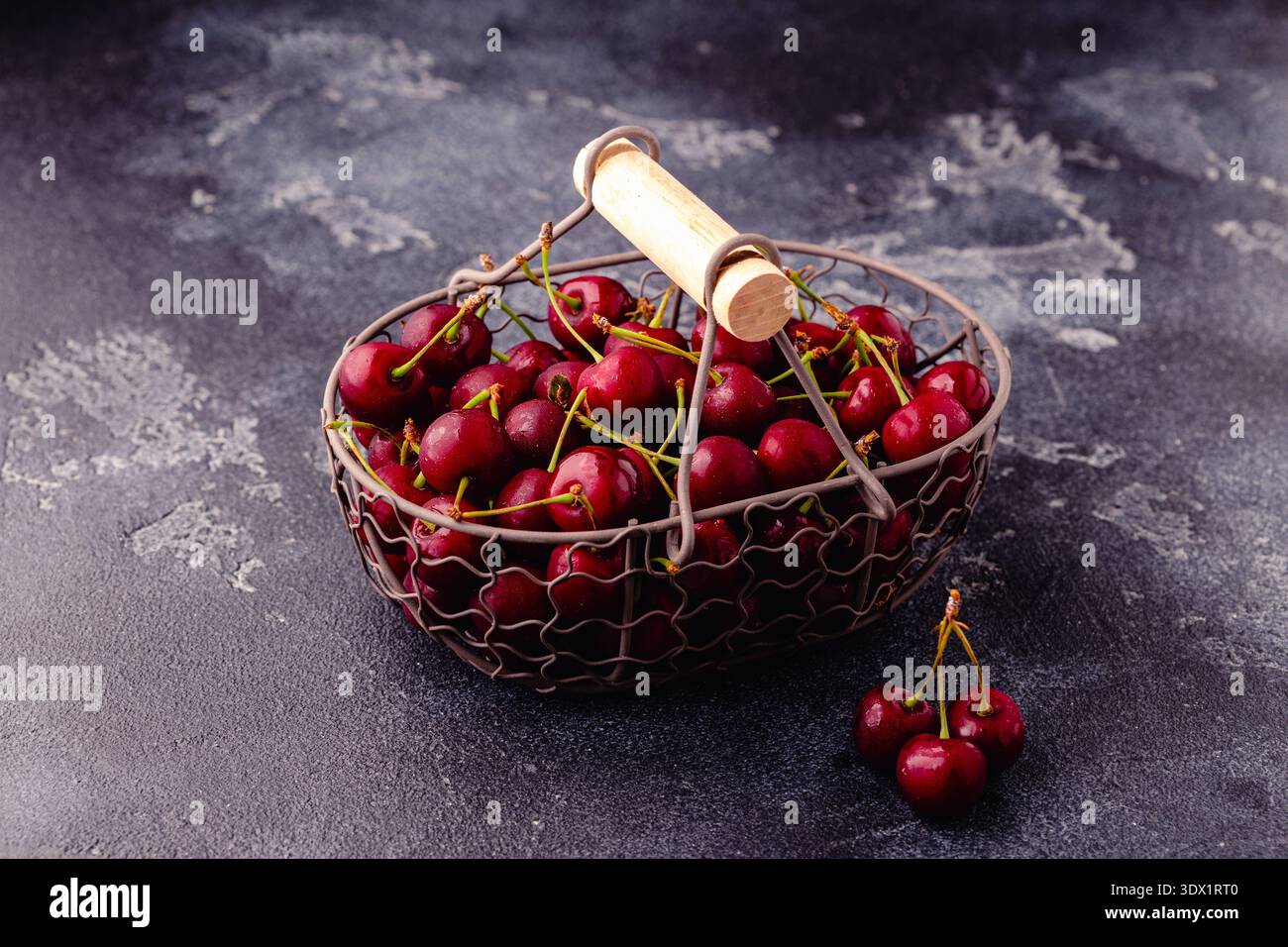 Cerises douces fraîches dans le panier sur fond sombre, mise au point sélective Banque D'Images
