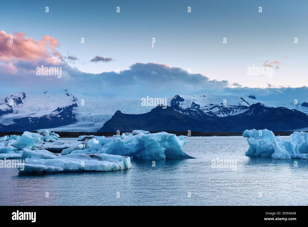 Paysage pittoresque de la lagune glaciaire de Jokulsarlon avec iceberg bleu flottant et croissant de lune dans le parc national de Vatnajokull, Islande Banque D'Images