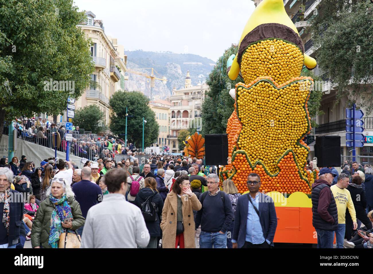 Flotteur de bananes géant fait d'oranges et de citrons tours au-dessus de la foule excitée pendant la célèbre Fête du citron parade de Menton.Menton, France Banque D'Images