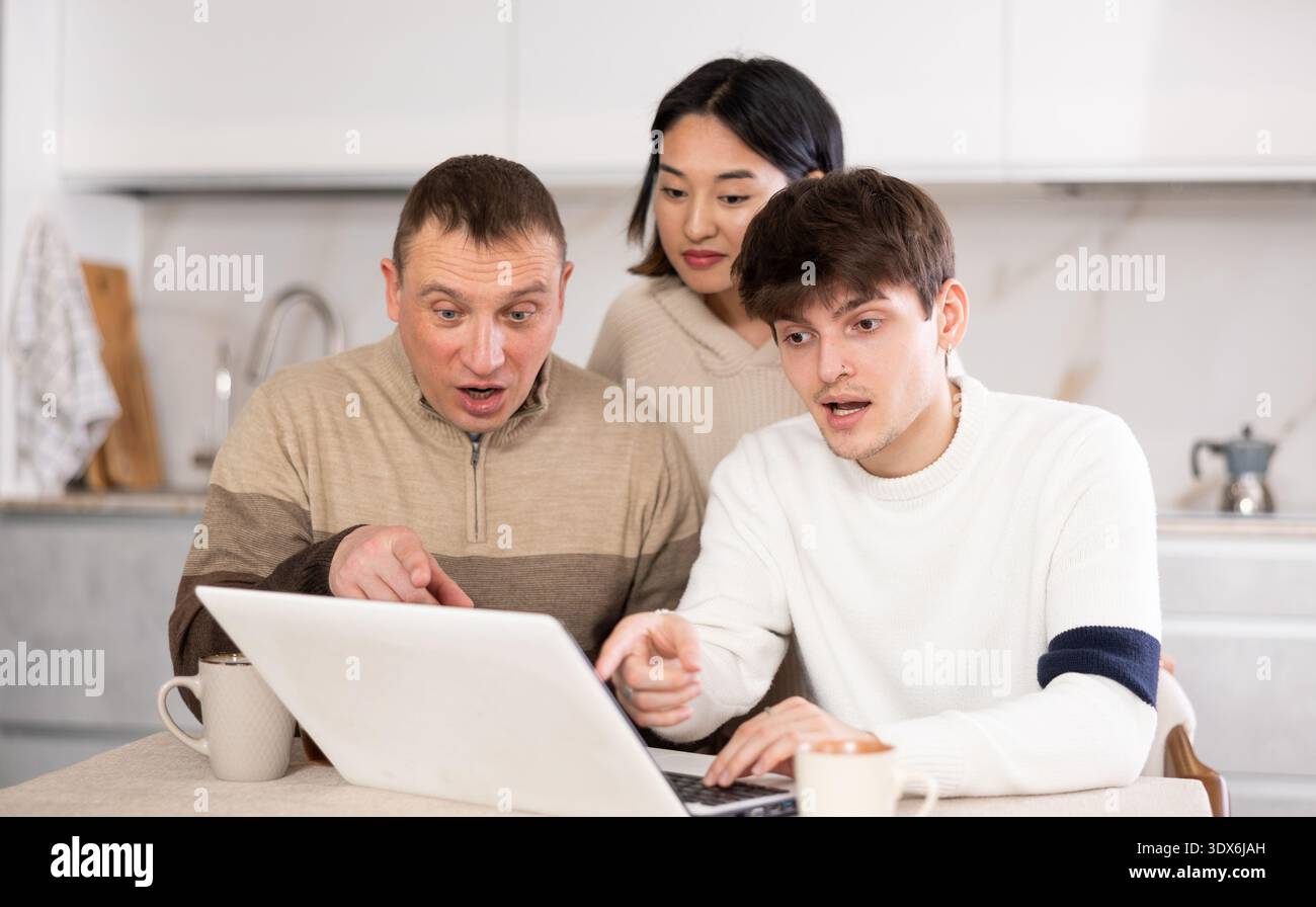 Une famille amicale regarde quelque chose ensemble sur Internet ou des chats vidéo via un ordinateur portable Banque D'Images