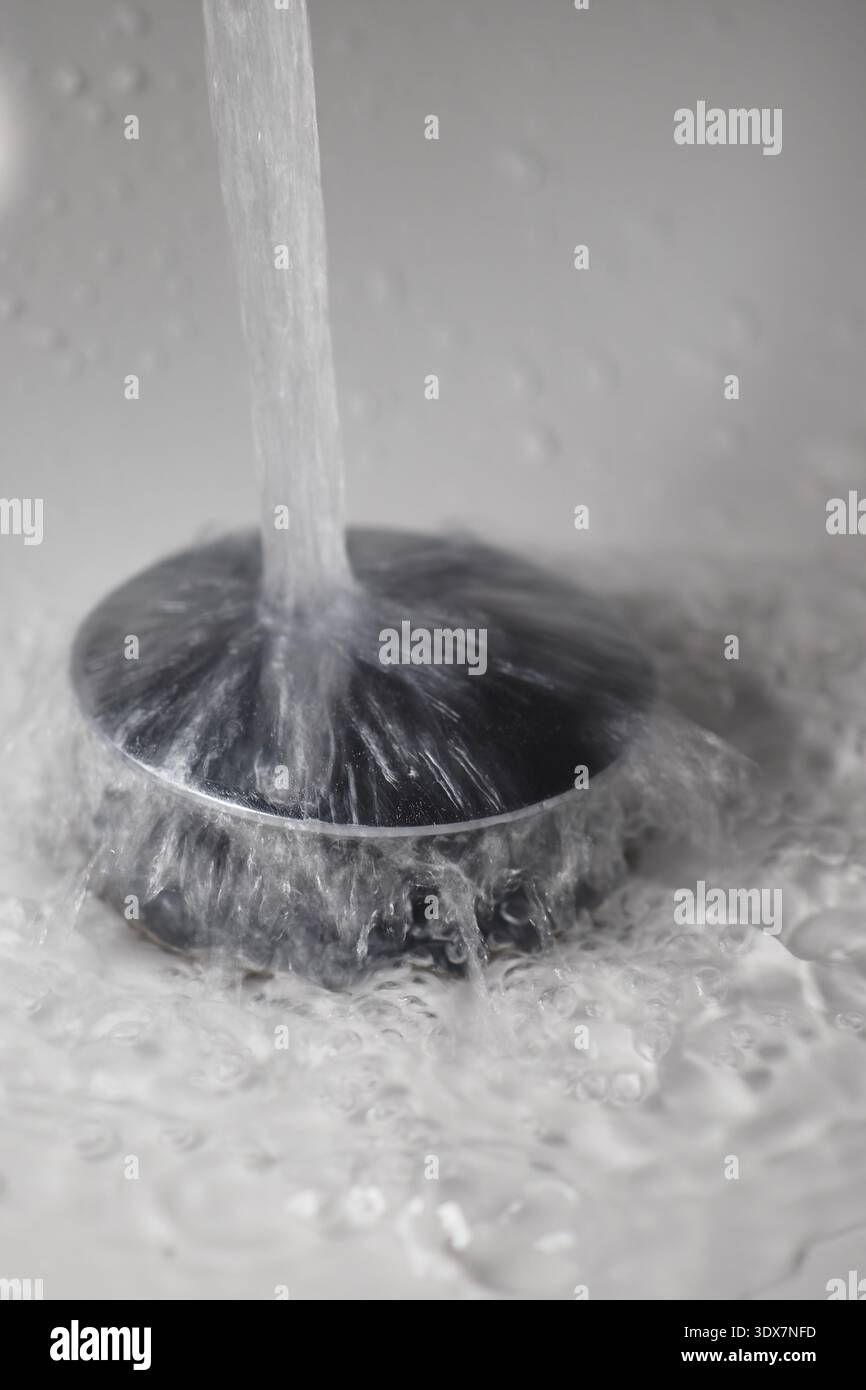 L'eau s'écoule du robinet dans le drain de l'évier Banque D'Images