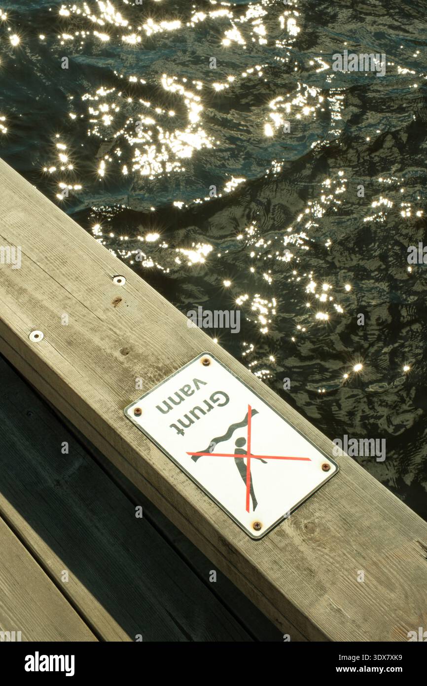 Oslo, Norvège - 29 juin 2024 : un panneau de sécurité sur une jetée en bois au port avertit les gens des eaux peu profondes et interdit la plongée Banque D'Images