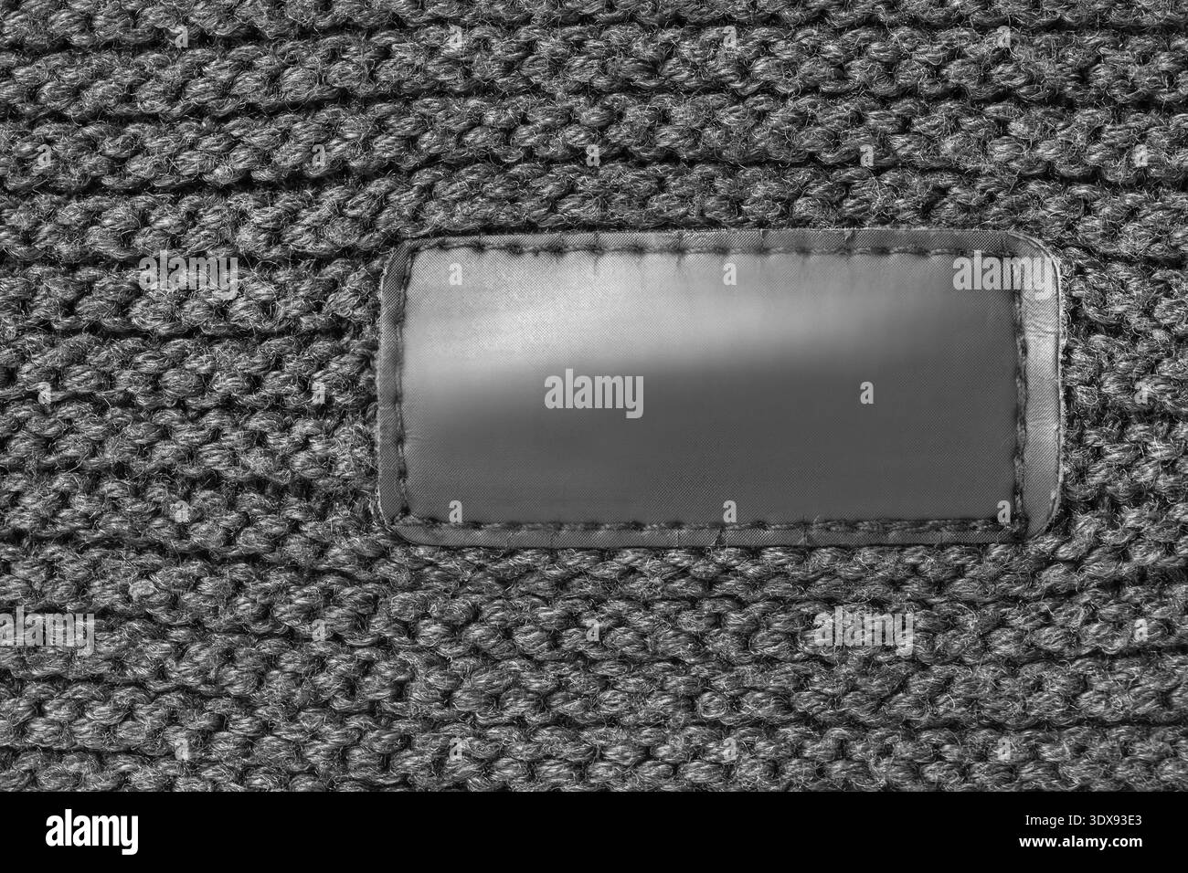 Étiquette de patch de vêtements noirs vierge cousue sur fond de tricot de fil noir Banque D'Images