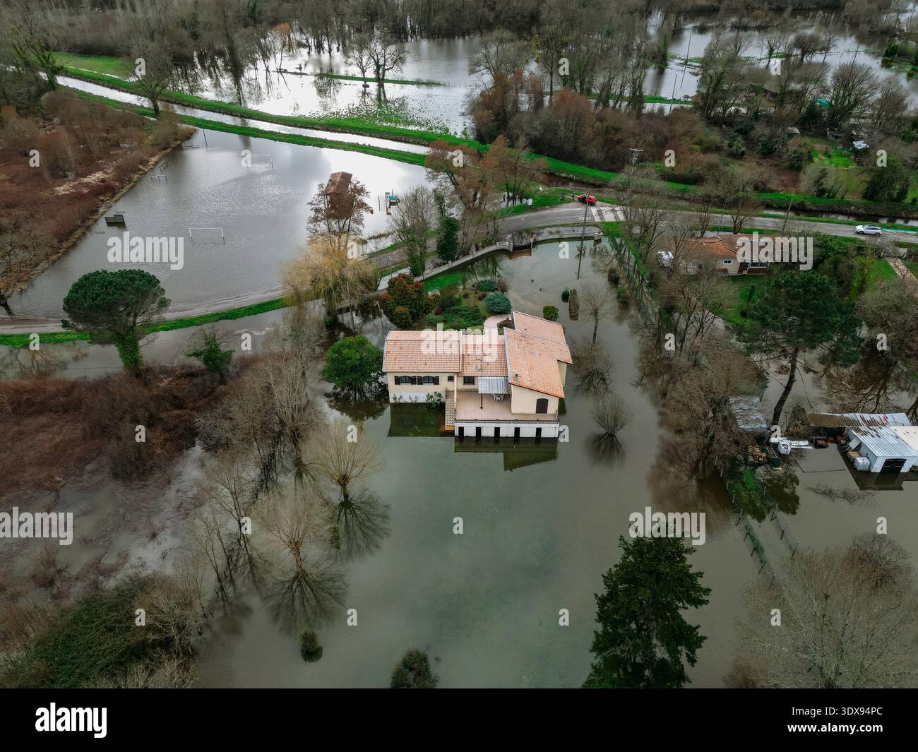 Isle-Saint-Georges, France - 20 février 2026 : vue aérienne d'une maison solitaire debout élastiquement au milieu des eaux de crue, reflétant le ciel sombre Banque D'Images