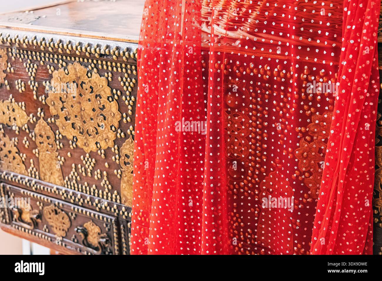 Coffre en bois culturel orné de riches ornements en laiton, de détails cloutés et de tissus rouges décoratifs drapés Banque D'Images