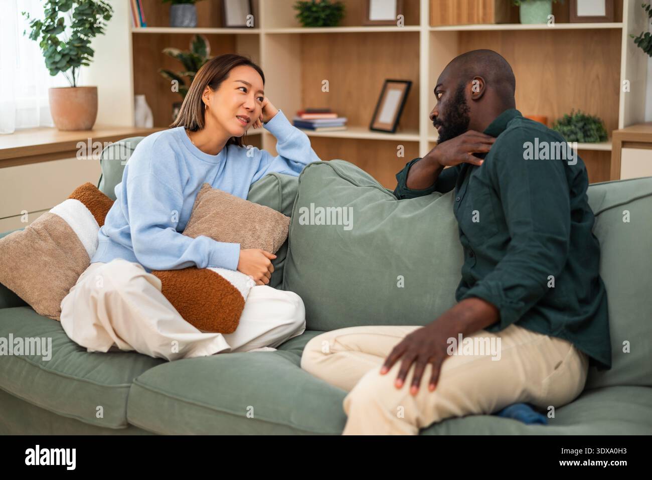Couple multiracial adulte assis sur le canapé à la maison à parler de leurs problèmes de santé. Banque D'Images