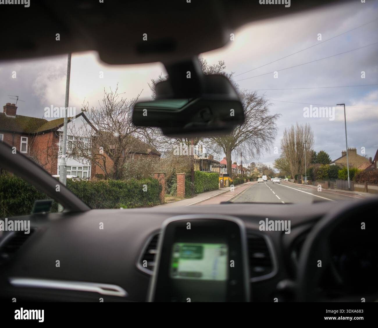 01 Mar 2026 - Cambridge, UK - Driving point of View - suivre un itinéraire dans un quartier anglais Redisdential avec des maisons et des maisons. Affichage de Sat Naviga Banque D'Images