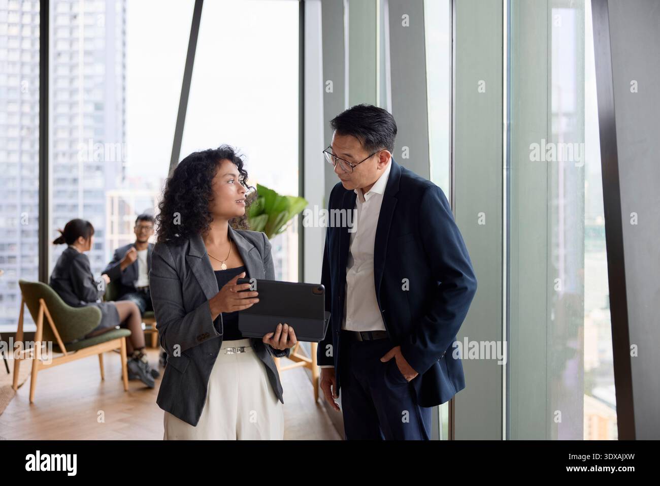 Homme d'affaires communiquant avec une collègue féminine tenant la tablette numérique au bureau Banque D'Images