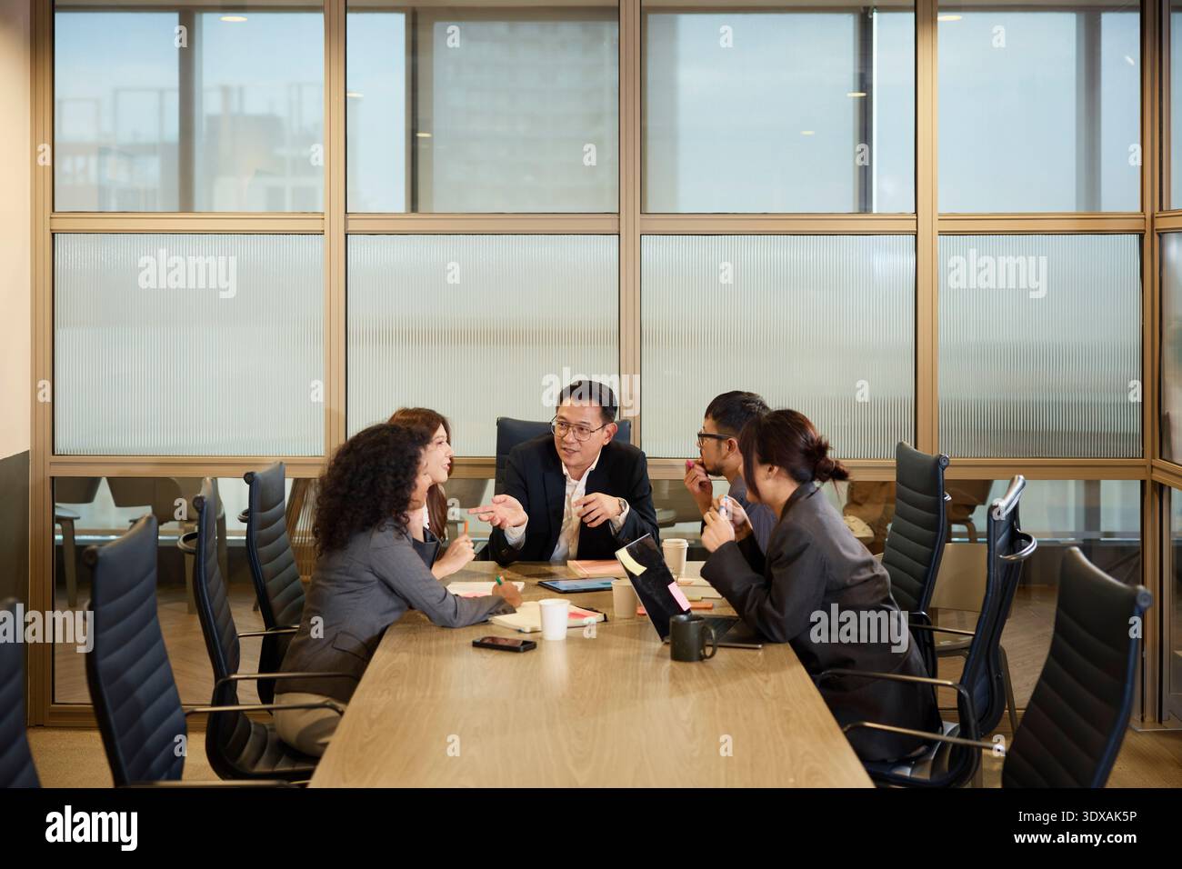 Responsable expliquant les stratégies aux collègues assis autour de la table dans la salle de réunion Banque D'Images