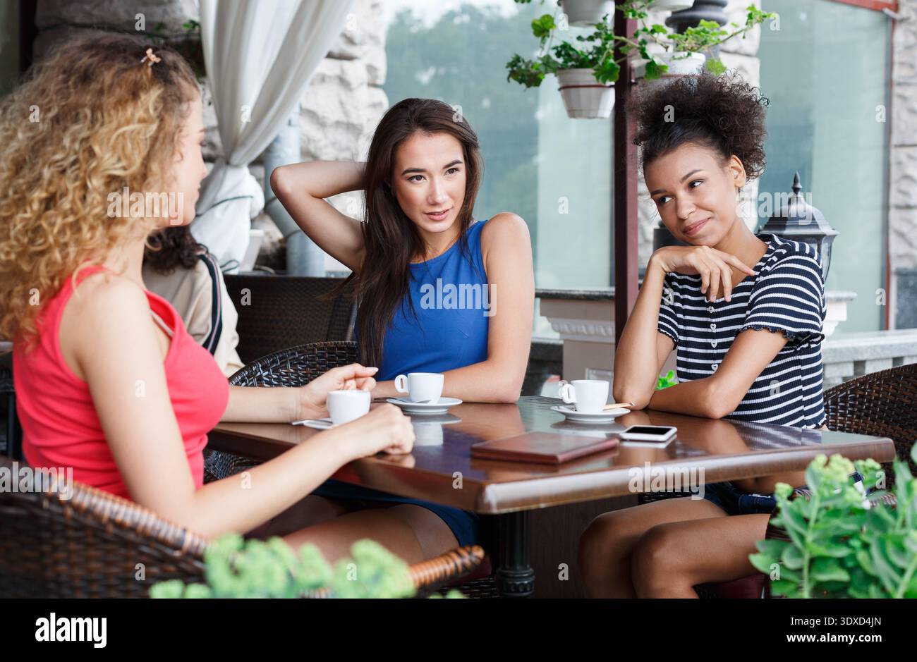 Les amis apprécient les boissons et la conversation dans un café pendant un après-midi ensoleillé en été Banque D'Images