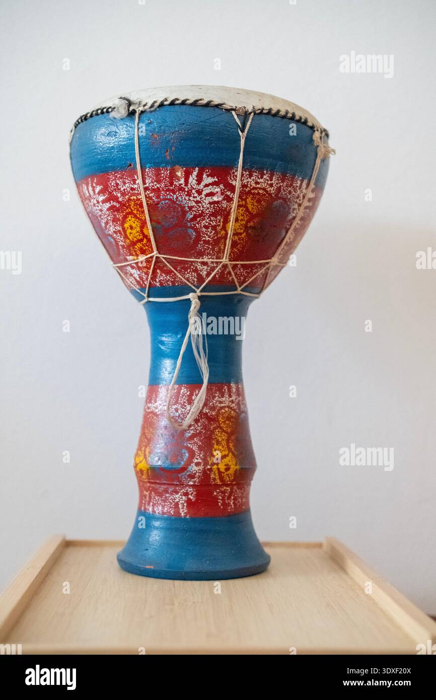 Petit tambour coloré d'origine africaine sur une plate-forme en bois. Le tambour a été photographié sur un fond clair Banque D'Images