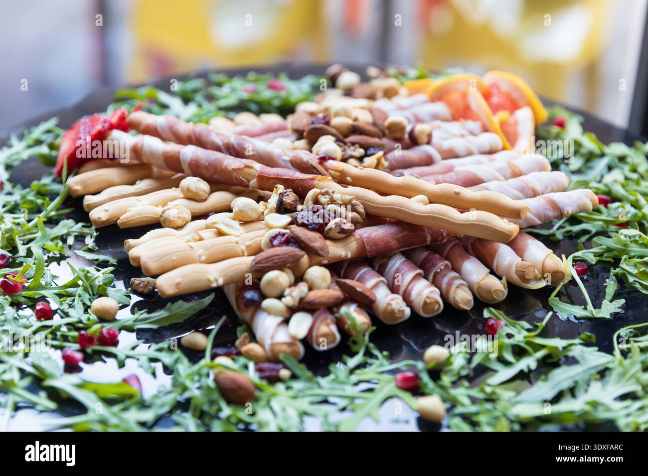Plat de charcuterie élégant avec gressins enveloppés de prosciutto, noix mélangées, baies séchées et roquette fraîche, parfait pour la restauration, l'apéritif de fête Banque D'Images
