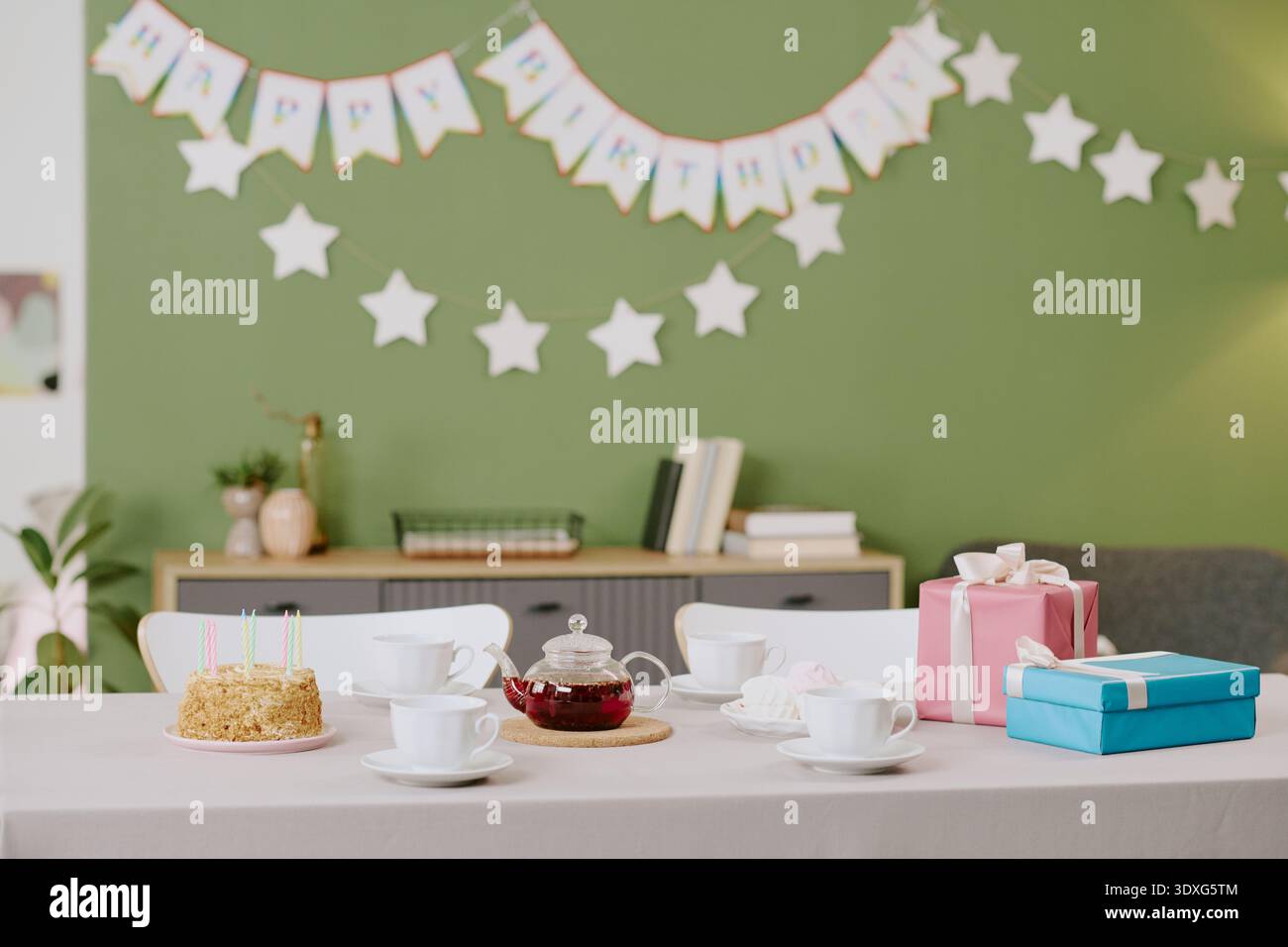 Table d'anniversaire avec gâteaux, thé et cadeaux emballés à l'intérieur Banque D'Images