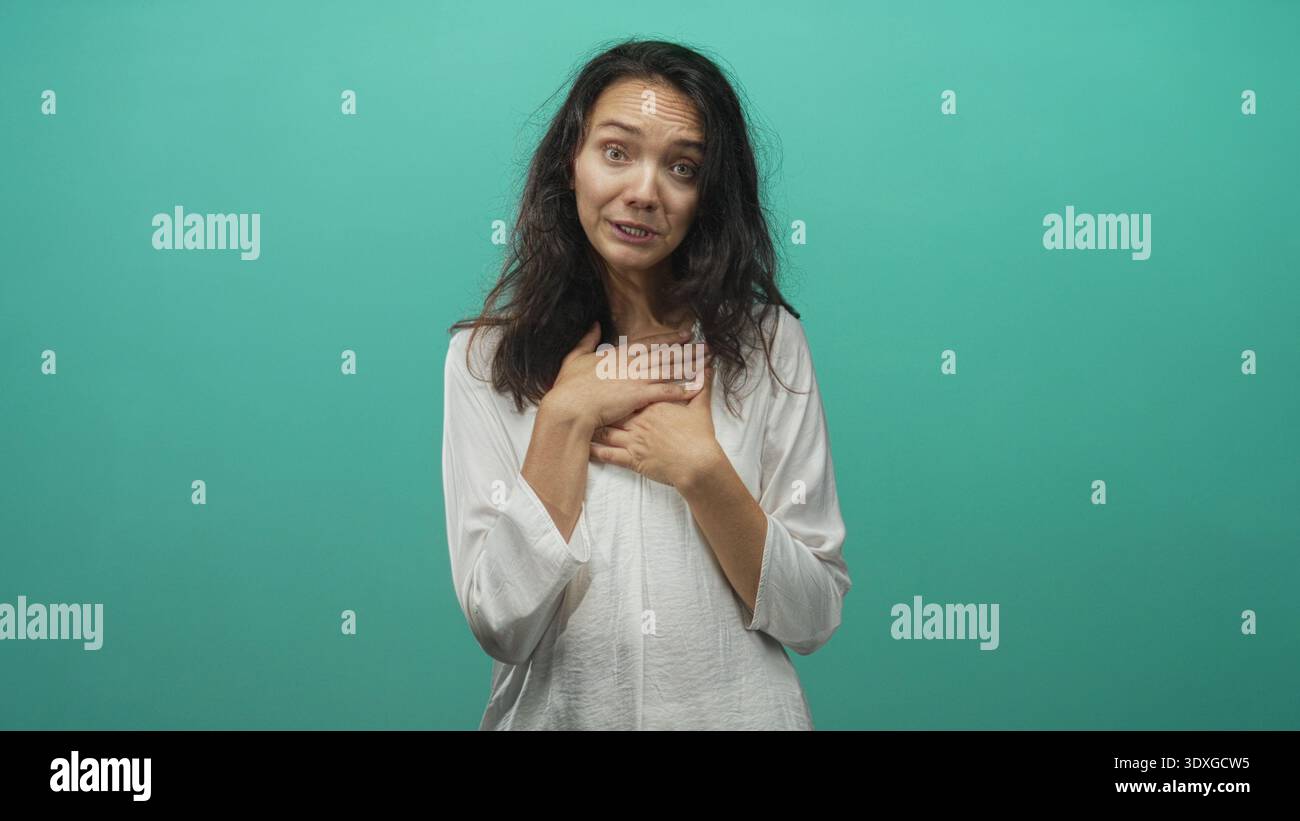 Femme pressant les mains sur la poitrine avec les yeux fermés dans une toile de fond de studio turquoise montrant un geste expressif de sincérité et de soulagement ; R réfléchi Banque D'Images