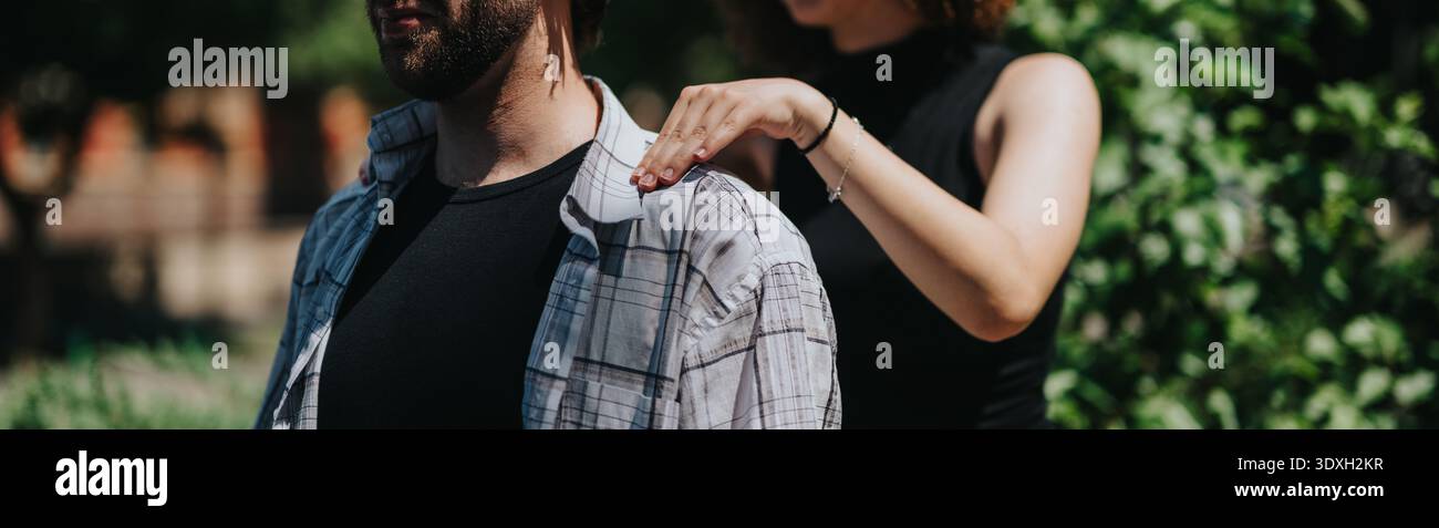Moment décontracté en plein air d'un homme avec une femme plaçant les mains sur ses épaules, détendu et amical Banque D'Images