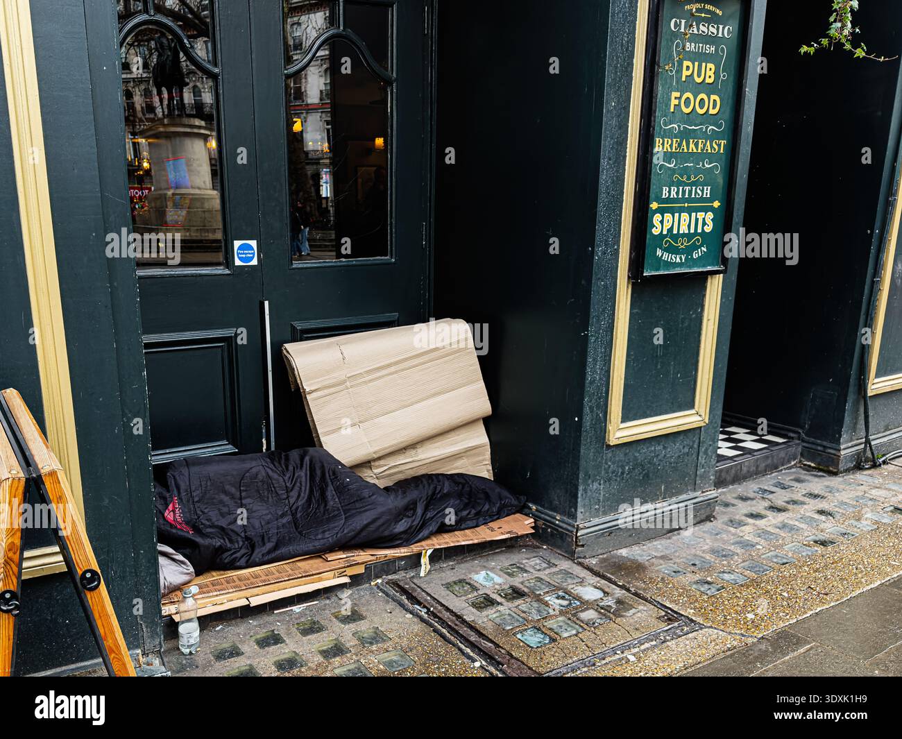 Londres, Royaume-Uni - février 01, 2026 : scène de rue londonienne avec un sans-abri endormi devant une porte de pub au Royaume-Uni. Banque D'Images