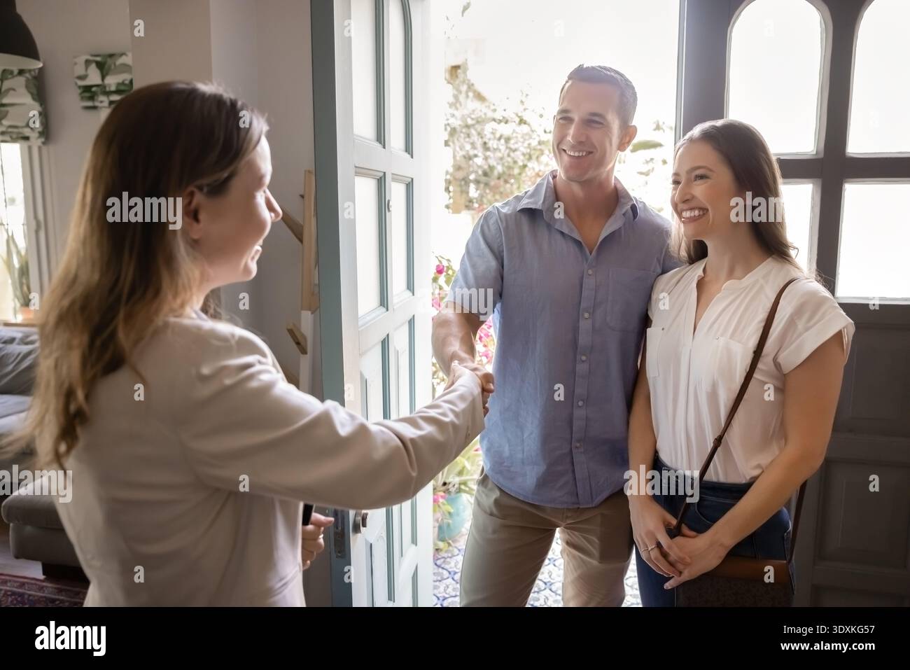Agent immobilier poignée de main avec couple, salutation, debout dans l'entrée de la maison Banque D'Images